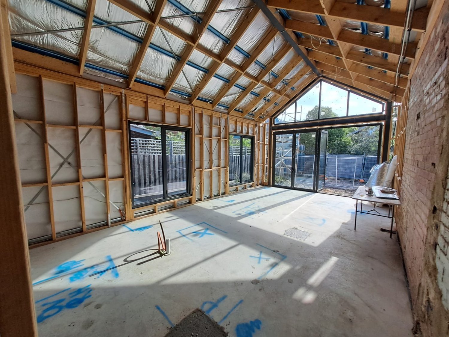 Timber-framed rear extension with raked ceiling and gable window during construction