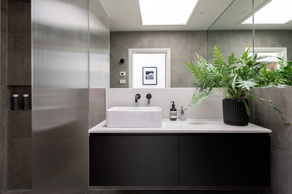 Bathroom with fluted glass shower screen, floating black vanity and skylight